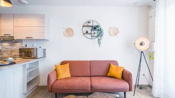 A modern living room with a sofa, a coffee table, a kitchen area, and a floor lamp.