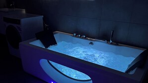 A modern bathroom with a built-in bathtub, a visible water heater, and a blue LED light strip along the tub's edge. - Magnifique Villa Avec vue sur le Luberon (Robion)