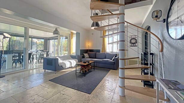 A spacious living area with a modern staircase, a comfortable seating area, and large windows offering a view of the outdoors. - Magnifique Villa Avec vue sur le Luberon (Robion)