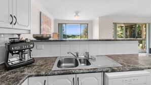 A modern kitchen with a coffee machine, double sink, and a view of the outdoors. - Ted's at Broulee (Broulee)