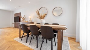 A modern dining area with a wooden table, dark chairs, and a white rug. - 3 Bedroom flat with Patio in Central London (London)