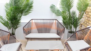 A seating area with wicker chairs and a table, surrounded by potted plants. - 3 Bedroom flat with Patio in Central London (London)