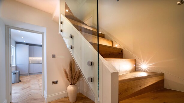 A modern staircase with glass railings and wooden steps, leading to an upper floor. - 3 Bedroom flat with Patio in Central London (London)