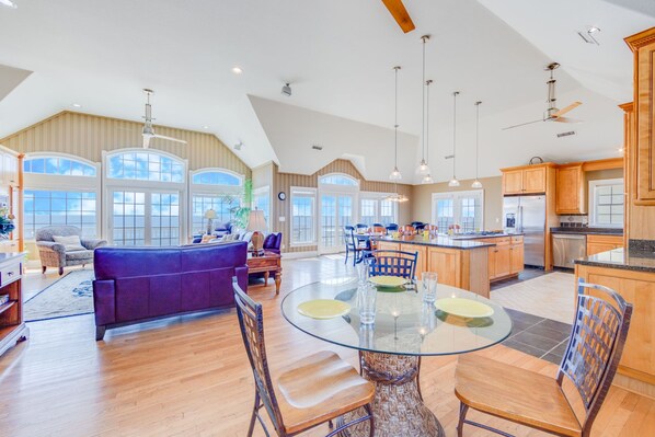 A spacious kitchen with a large island, wooden cabinets, and a dining area with a glass table and chairs.
