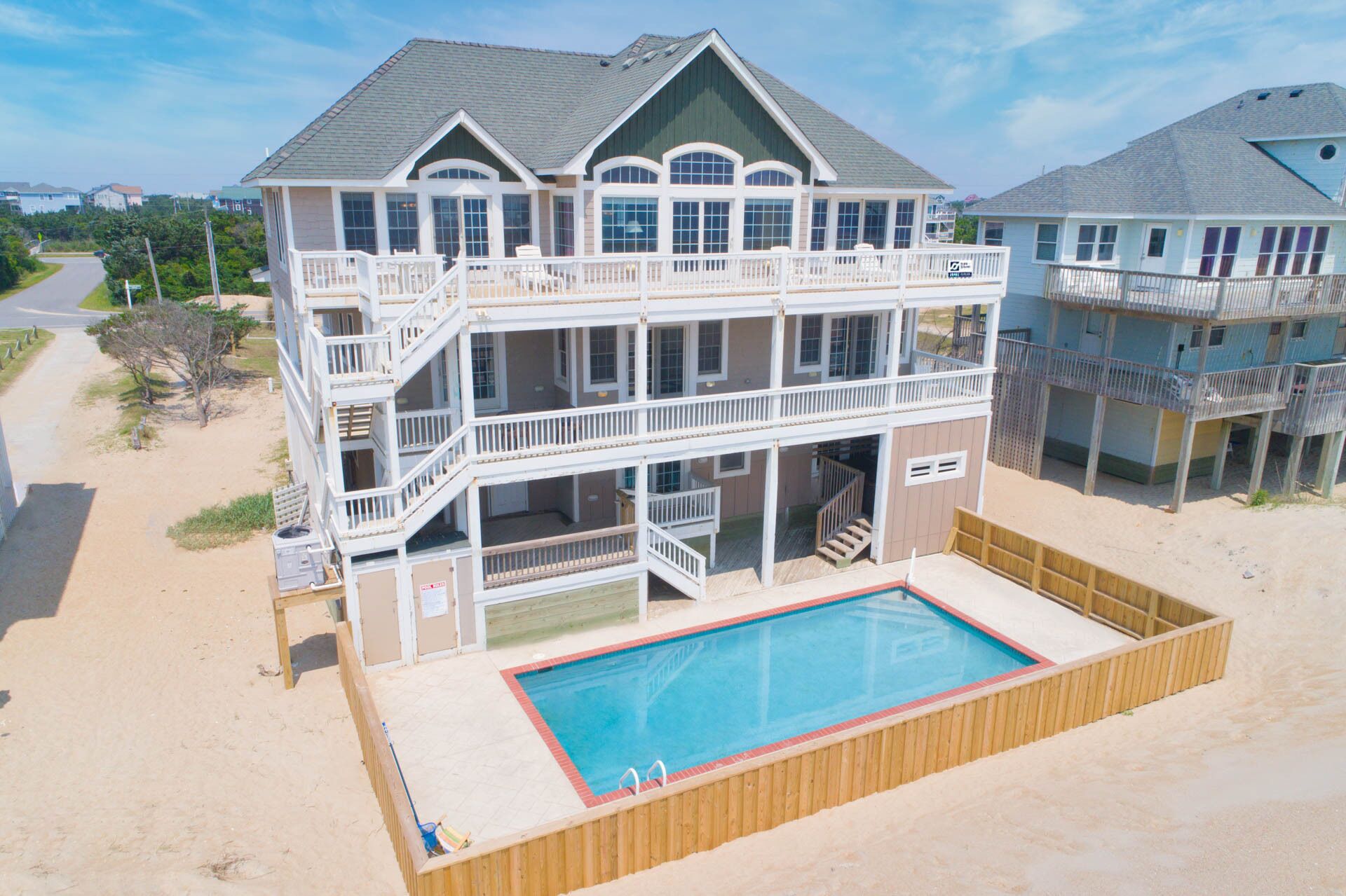 Une maison de deux étages située en bord de mer, dotée d’une piscine et d’une terrasse couverte.