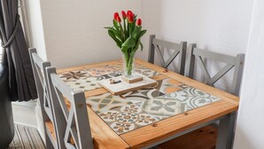 A small wooden table with a patterned tablecloth, a vase with red flowers, and a notebook. - Beach (Bridlington)