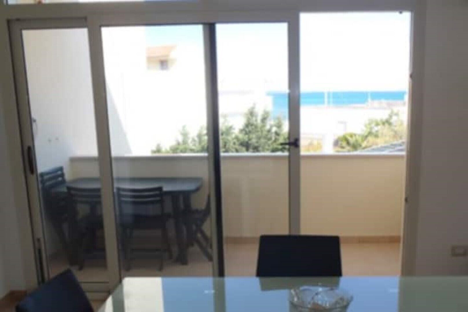 Quarto com porta de vidro deslizante para varanda com mesa e cadeiras.