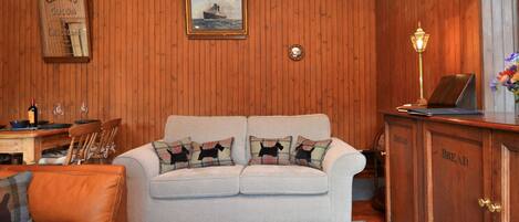 A cozy living room with a light-colored sofa, a wooden cabinet, and a framed picture on the wall.