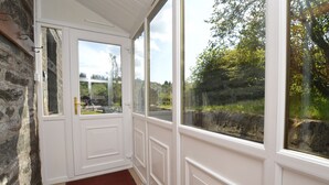Una habitación con pared de piedra, una puerta blanca con paneles de vidrio y vistas a zonas verdes.
