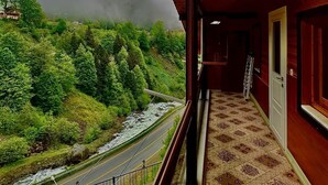 A room with a view of a river and forest, a patterned carpet, and a wooden ceiling. - Konak Grand Apart (Çaykara)