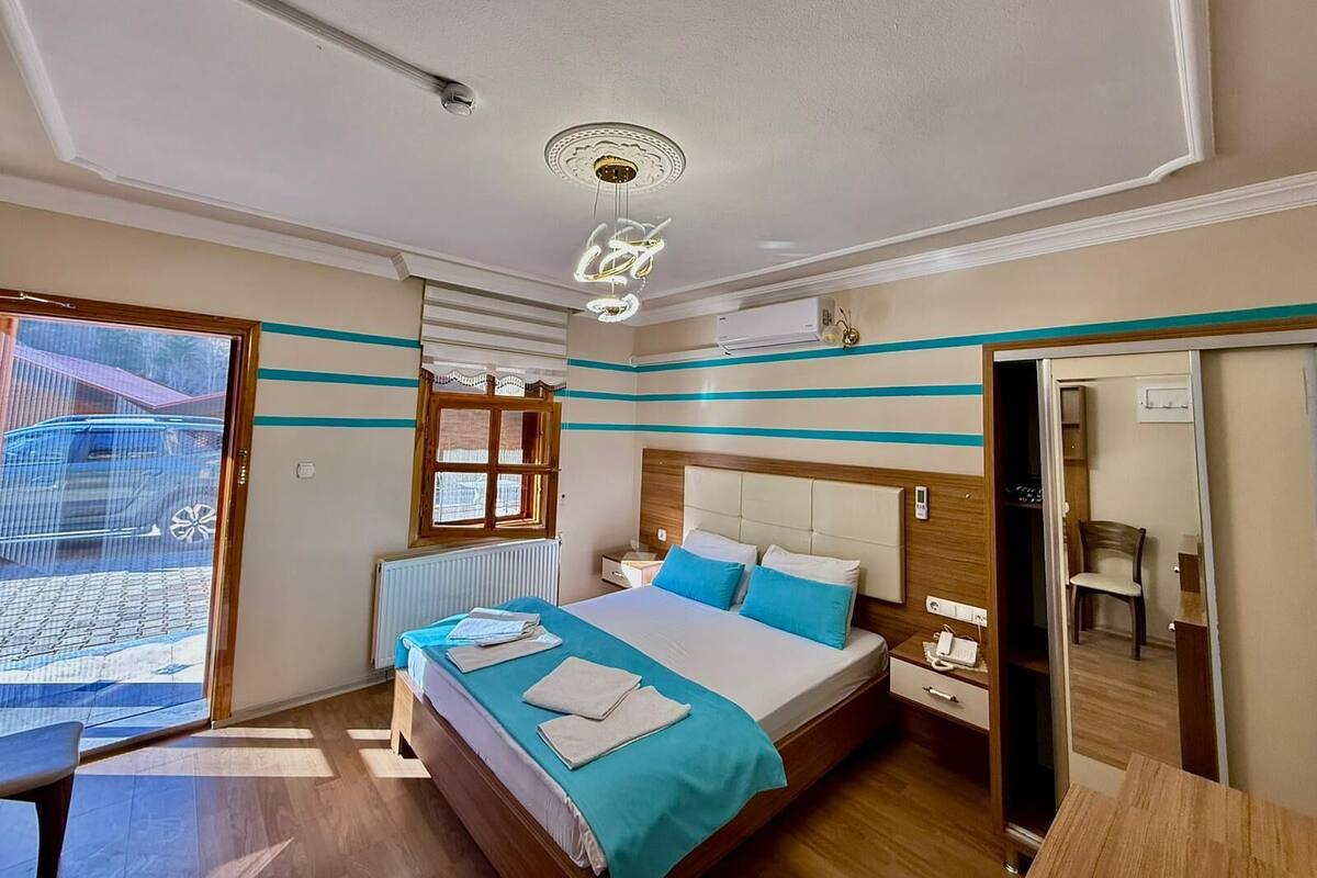 Habitació d'hotel amb un llit, una taula de nit i una finestra amb persianes.