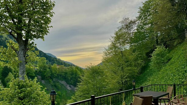 A balcony with wicker furniture and a view of a valley. - Konak Grand Apart (Çaykara)