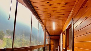 A corridor with wooden walls and large windows offering a view of a mountainous landscape. - Konak Grand Apart (Çaykara)