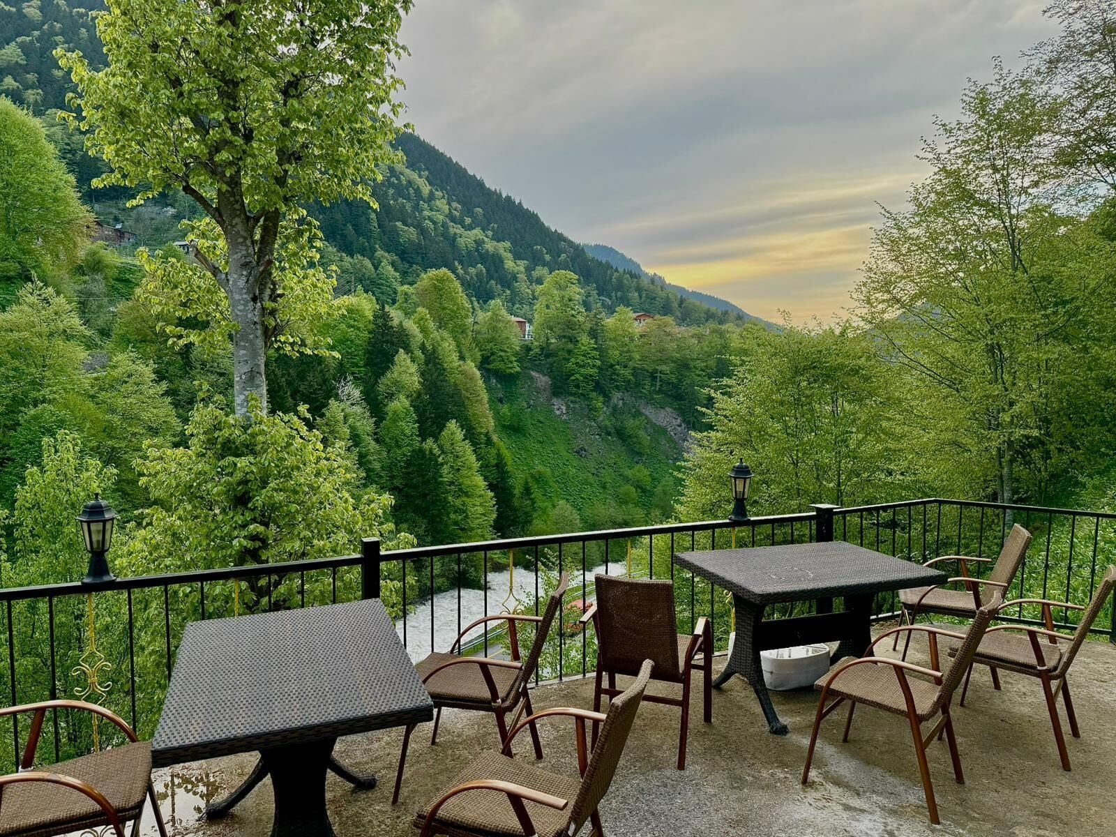 A terrace with tables and chairs, overlooking a forested valley.