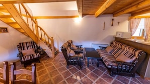 A cozy living area with a wooden staircase, striped sofas, and a tiled floor. - Villa Dolina Miru (Zavrc)