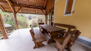 An outdoor wooden table and benches under a covered area with a view of the surrounding landscape. - Villa Dolina Miru (Zavrc)