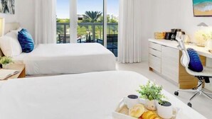 Een hotelkamer met twee bedden, een bureau, een stoel, een raam met gordijnen en een schilderij aan de muur.