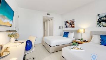 Una habitación de hotel con cama, mesita de noche, lámpara y obras de arte en las paredes.