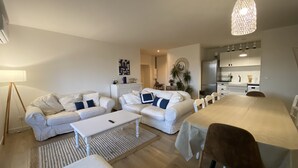 A modern living room with two white sofas, a coffee table, and a dining table with chairs. - T4 Bord Canal du Midi, Piscine (Homps)