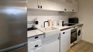 A compact kitchen with white cabinetry, a built-in dishwasher, a microwave, and a stove. - T4 Bord Canal du Midi, Piscine (Homps)