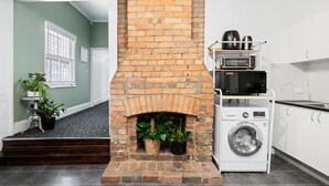 Un espace buanderie avec une cheminée en briques, un lave-linge et un four à micro-ondes posé sur une étagère.