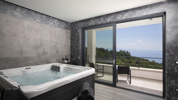 A modern bathroom with a hot tub, a balcony with a view, and a large sliding glass door. - Villa Ziganto with a view of the Kvarner Bay (Poljane)