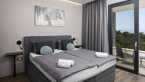 A modern bedroom with a large bed, a nightstand, a wall-mounted lamp, a painting, and a sliding glass door to a balcony. - Villa Ziganto with a view of the Kvarner Bay (Poljane)