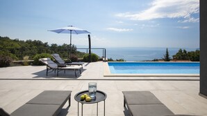 A poolside area with lounge chairs, a table with lemons, and a view of the sea. - Villa Ziganto with a view of the Kvarner Bay (Poljane)