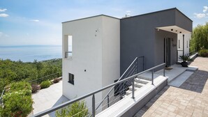 A modern two-story building with a balcony, a view of the sea, and a landscaped garden. - Villa Ziganto with a view of the Kvarner Bay (Poljane)