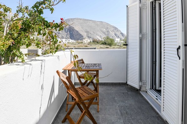Enjoy a mountain view from this balcony with a table and two chairs.