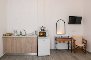 Compact kitchenette with microwave, refrigerator, and workspace.