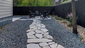Un jardin avec un chemin de pierres menant à du mobilier d’extérieur.
