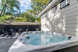 Ein Whirlpool in einem Garten mit Holzzaun, Stühlen und einem Haus im Hintergrund.