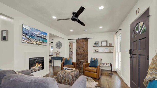 Un salon doté d’une cheminée, d’un ventilateur de plafond et d’une grande fenêtre.