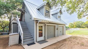 A two-story house with a garage, a covered porch, and a staircase leading to the upper floor. - Red Bird Cabin - Studio Retreat (Kingsland)