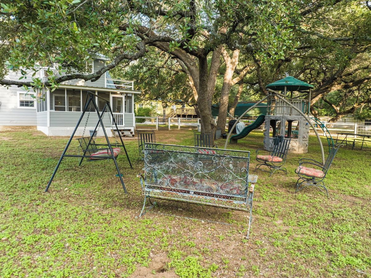 A playground with a swing set, a bench, and a tree.