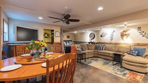 A spacious living area with a dining table, sofa, and decorative wall art. - Red Bird Cabin - Studio Retreat (Kingsland)