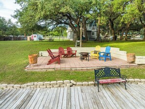 A wooden deck with outdoor furniture, a fire pit, and a stone border. - Red Bird Cabin - Studio Retreat (Kingsland)