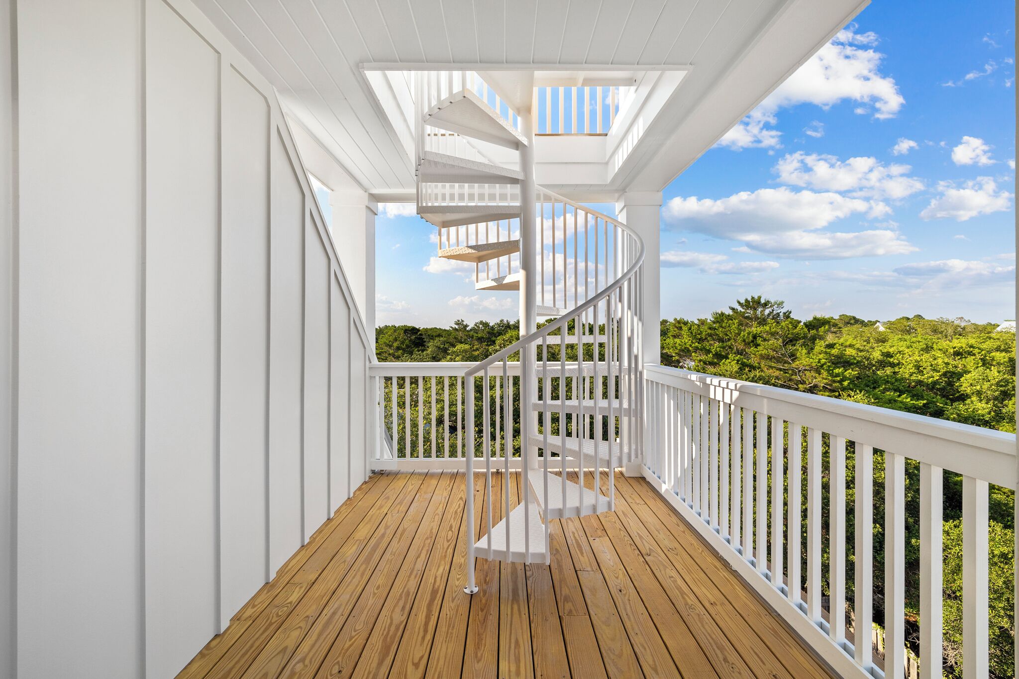 A wooden deck with a white spiral staircase and white railings.