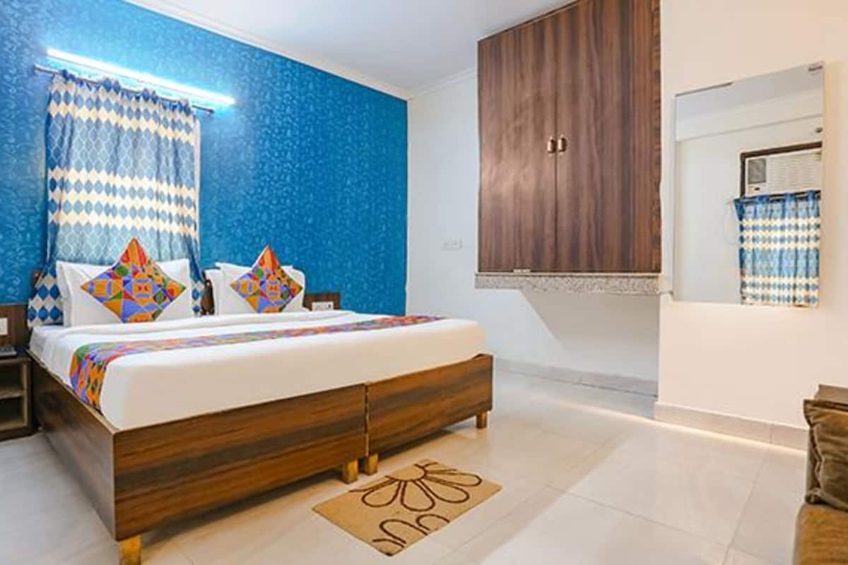 A bedroom with a bed, nightstands, a wooden wardrobe, and a window with curtains.