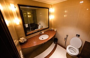 A modern bathroom with a large mirror, a sink, a toilet, and a shower area.