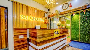 A reception desk with a wooden finish and a neon sign that reads "SAI CHATA". - FabHotel Sai Chatra (Nashik)