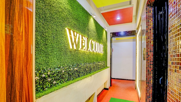 A reception area with a 'WELCOME' sign on a green wall, a red carpet, and a tiled wall to the right. - FabHotel Sai Chatra (Nashik)