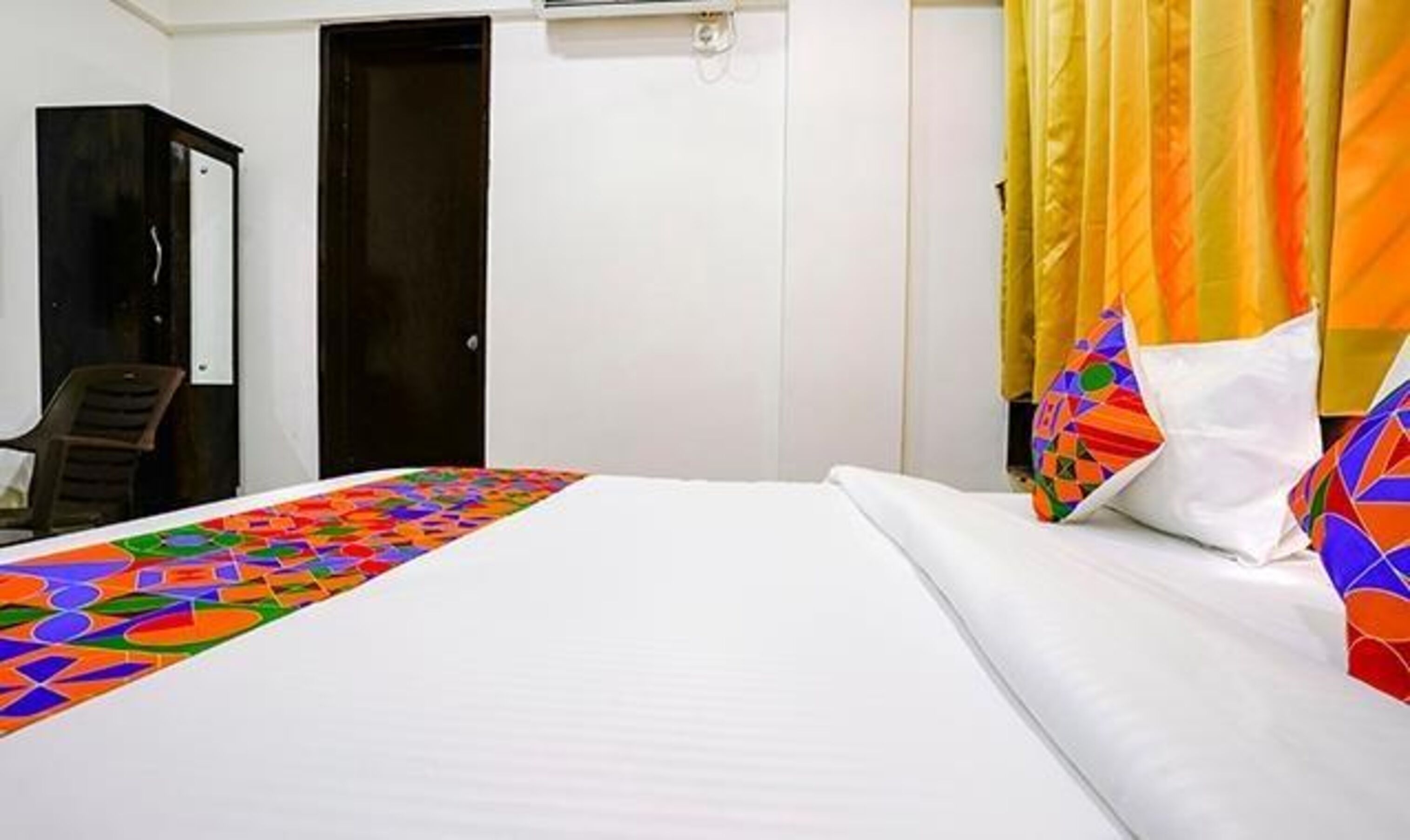 Een hotelkamer met een bed, een stoel, een kast en een deur.
