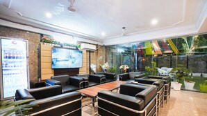 A modern lounge area with leather sofas, a wooden coffee table, and a flat-screen TV. - Fabhotel Tanvi Premium (Gurugram)