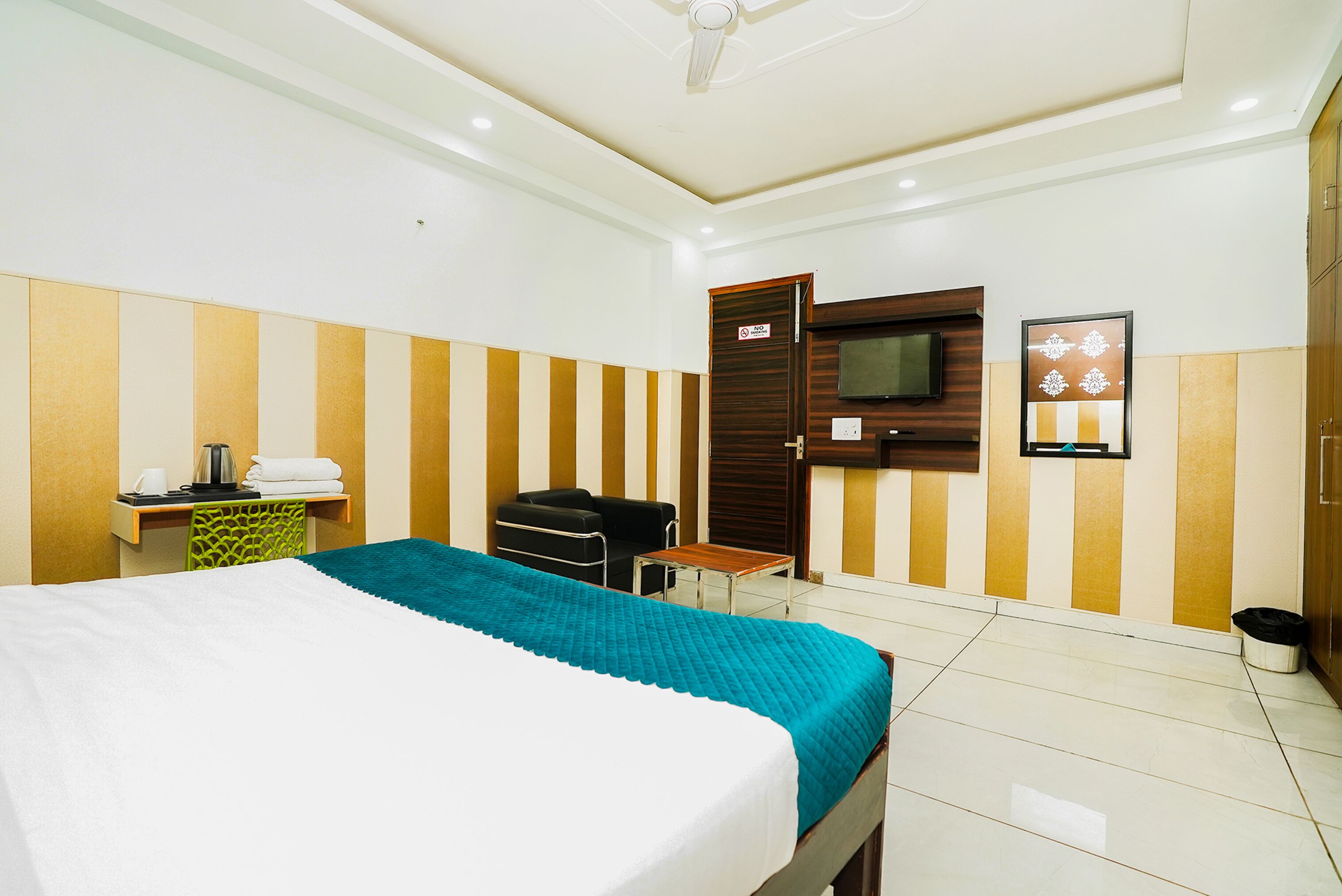 A hotel room with a bed, a desk, a chair, a TV, and a wardrobe.
