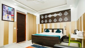 A hotel room with a bed, a desk, a chair, a coffee maker, and a painting on the wall. - Fabhotel Tanvi Premium (Gurugram)