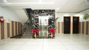 A hotel lobby with a marble reception desk, a staircase, and two elevators. - Fabhotel Tanvi Premium (Gurugram)