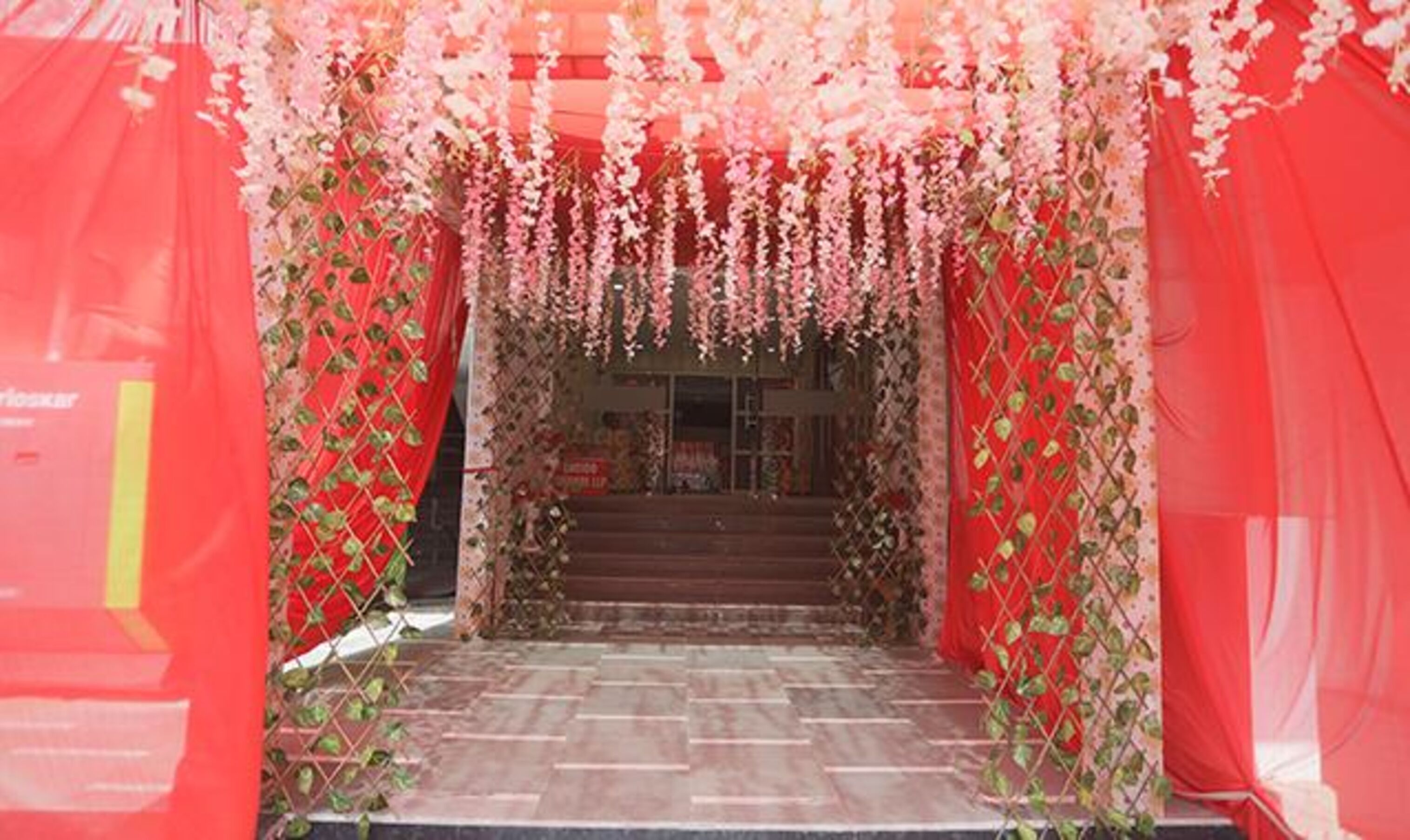 A staircase leading to a building entrance, surrounded by red drapes and floral decorations.