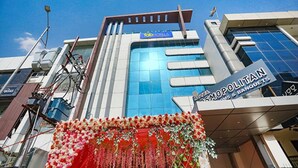 Un bâtiment d’hôtel moderne, avec une enseigne « fab hotels », une enseigne « Hotel Cosmopolitan » et un balcon agrémenté de décorations florales.
